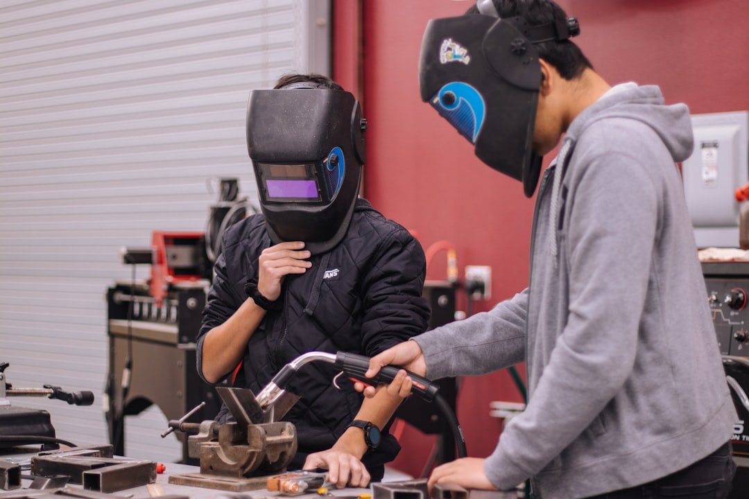 Welder using hand-guided programming to teach a collaborative robot a new weld path on a metal fixture